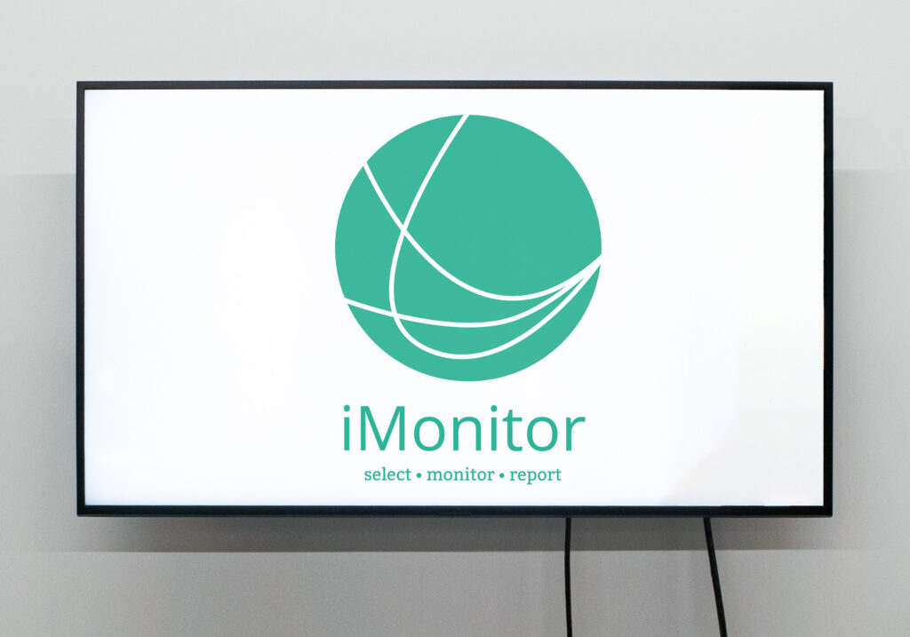 large tv with the logo of imonitor, a green circles with 3 lines inside and the tagline select, monitor, report