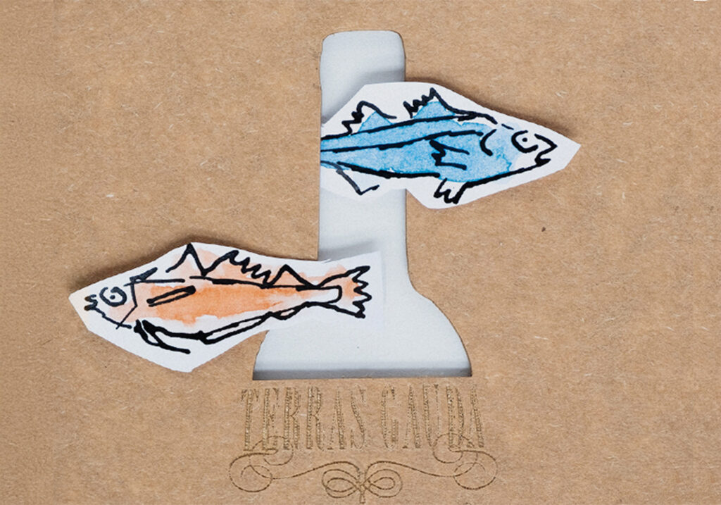 a close up of ink drawn fish and a laser cut bottle and logo "Terras Gauda" for the wine make Terras Gauda