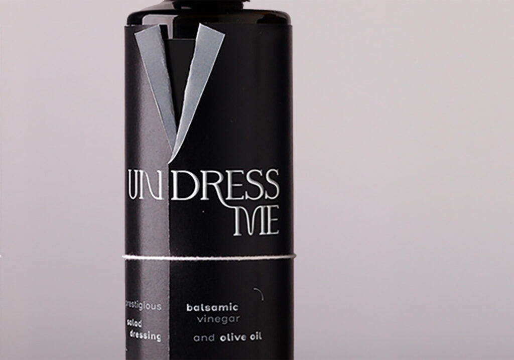 One bottle of vinegar with a label in the shape of a jacket, with as title undress me, printed in silver