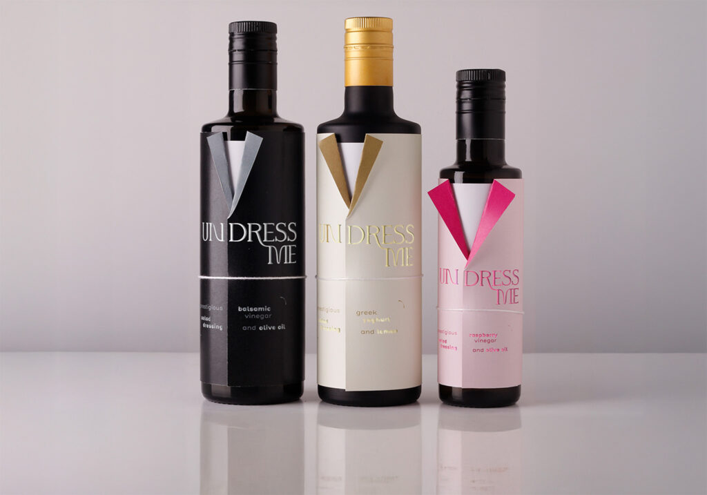 Three bottles of vinegar with a label in the shape of a jacket, with as title undress me, and a white undershirt under 
